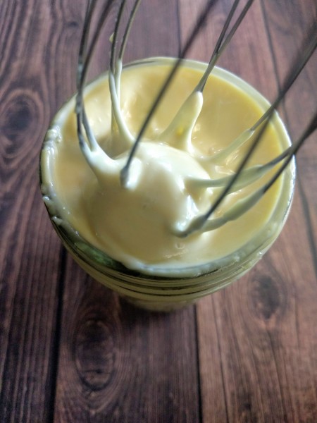 Homemade mayonnaise with whisk in jar.